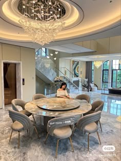 a woman is sitting at a round table in the middle of a room with chandelier