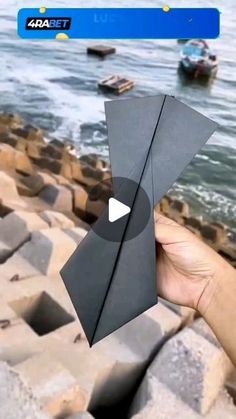 someone is holding up an origami piece near the water