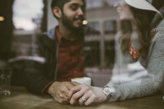 a man and woman sitting at a table holding hands