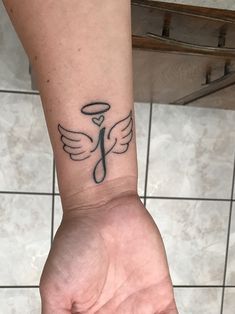 a person's arm with a tattoo on it that has an angel wing in the middle