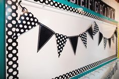 black and white polka dot bunting hanging on the wall in front of a sign