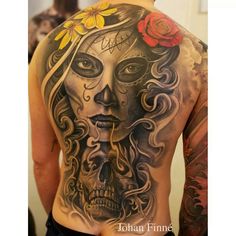 a man with tattoos on his back has a flower in his hair and skull face