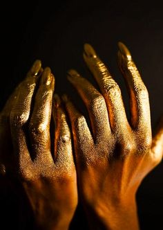 two hands with gold paint on them