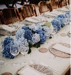 a long table is set with blue flowers and place settings for the guests to sit at