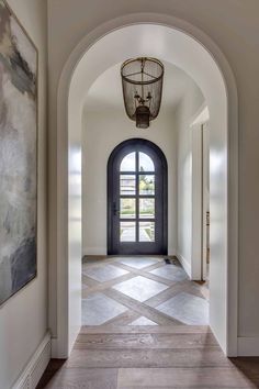 an archway leading into a foyer with a black door and large painting on the wall