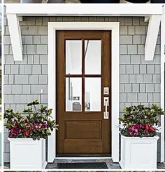 the front door is decorated with flowers and potted plants, along with two white planters