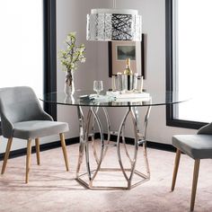 a glass table with chairs around it in front of a mirror and vase on the wall