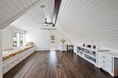 an attic bedroom with white walls and wood flooring, built in shelving units