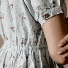 a close up of a person wearing a dress and holding their hand on her wrist