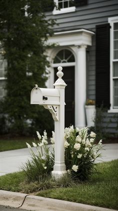 a white mailbox sitting in front of a house with flowers growing out of it