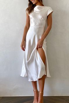 a woman wearing a white dress with a slit down the side and heels on her feet