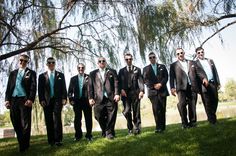 a group of men in suits and sunglasses standing next to each other under a tree