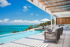 an outdoor pool with chairs and umbrellas next to the ocean