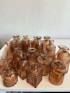 an assortment of brown glass vases sitting on top of a white table next to each other