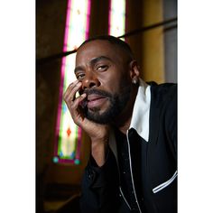 a man sitting in front of a stained glass window talking on a cell phone while holding his hand to his ear