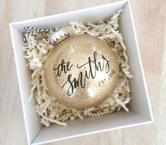 a personalized ornament in a box with white shredded paper on the floor