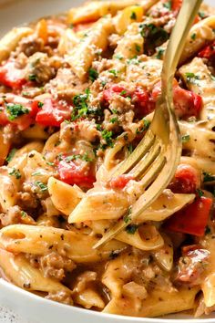 a fork in a bowl full of pasta with meat and vegetables on it, ready to be eaten