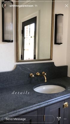 a bathroom sink sitting under a mirror next to a counter top with gold faucets