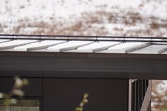 a bird is perched on the roof of a building with snow covered mountains in the background