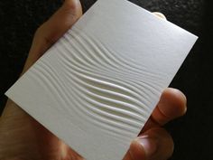 a hand holding a piece of white paper with wavy lines on the top of it