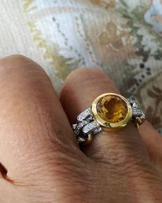 a woman's hand holding a yellow and white diamond ring