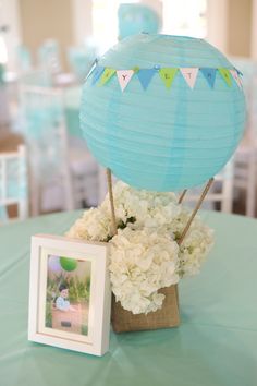 there is a blue hot air balloon on the table with flowers in front of it