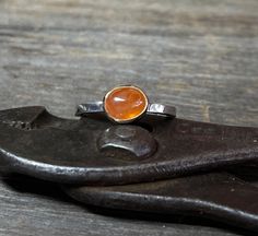 A vibrant oval Spessartite Garnet (also known as Mandarin) gemstone is set in solid 14k gold and is perched atop a sterling silver band. Perfect on its own, or a brilliant addition to your stack. Size 7.5 Garnet: 8mm x 6mm, 3.23cts Band: 2.10mm Will arrive gift-boxed. This is a natural, untreated Mandarin Garnet, not synthetic, so there will be naturally occurring inclusions. Inclusions are not considered a defect, but rather the unique personality of each stone. My jewelry is handcrafted one piece at a time by me in my home studio in Portland, Oregon. If I can help you with any questions about this piece or any of my other products, please feel free to contact me: hello @ paulla.com PIN IT on PINTEREST FOLLOW on Instagram - @paullatewksburyjewelry LIKE IT on Facebook - @paullatewksburyjew Oval Orange Sapphire Ring For Gift, Orange Oval Sapphire Gemstone Ring, Orange Sapphire Ring In 14k Gold For Gift, Oval Orange Sapphire Ring As Gift, Orange Oval Sapphire Ring, Orange Sapphire Round Ring, Heirloom Orange Ring For Gift, Heirloom Style Orange Ring For Gift, Heirloom Orange Ring As Gift