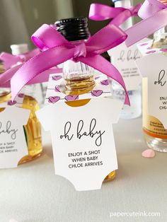 baby shower favors with bottle labels and pink ribbon on the top, sitting on a table