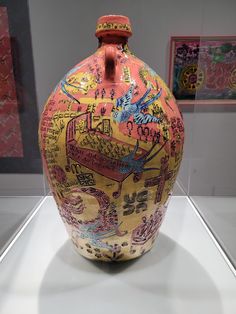 a colorful vase with writing on it in a display case at a museum or art gallery