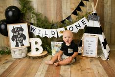 a baby boy sitting on the floor in front of some black and white decorations with letters