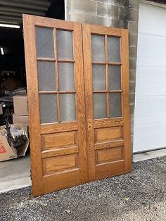 two wooden doors are open in front of a garage with boxes on the ground next to it