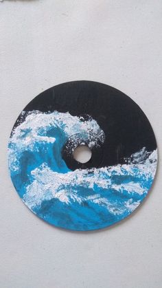 a blue and black disk with waves painted on the disc is sitting on a white surface