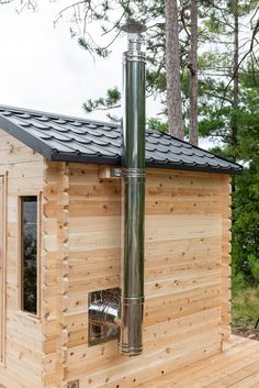 a small wooden cabin with a metal chimney on the roof and wood sidings around it