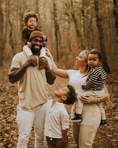 a group of people standing around each other in the woods with one holding a baby