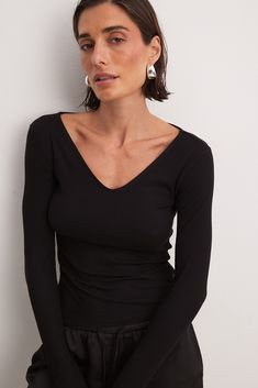 This long sleeve top features a form fit and a ribbed stretchy material. It has a V-neck. Ribbed V-neck Elastane Top, Trendy Ribbed Bodycon Top, Winter V-neck Elastane Top, Black Fitted Long Sleeve V-neck Top, Black Fitted V-neck Long Sleeve Top, Fitted Black V-neck Long Sleeve Top, Bodycon Long Sleeve Tops For Fall, Seamless Long Sleeve Top For Fall, Fall Bodycon Long Sleeve Tops