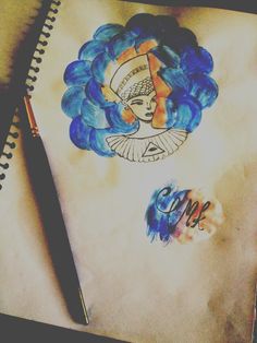 a drawing of a woman with blue hair on top of a piece of paper next to a pen