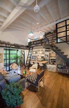 a living room filled with furniture and bookshelves next to a stair case full of books