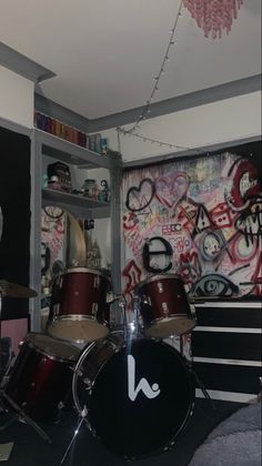 a room filled with lots of musical instruments and graffiti on the wall behind it's drum set