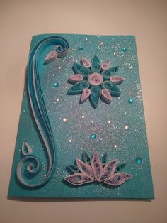 a blue card with white and pink flowers on it, sitting on top of a table