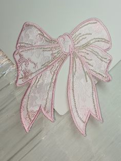 a pink and white lace bow on top of a piece of paper that is taped to the wall