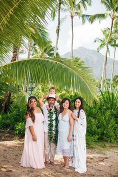 a group of people standing next to each other in front of palm trees and mountains