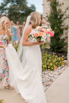 two brides are walking down the sidewalk with their bouquets