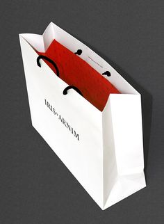 an open white shopping bag with red handles