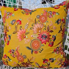 a yellow floral pillow sitting on top of a white chair