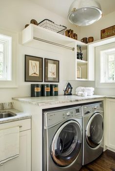 a washer and dryer in a room with pictures on the wall above it