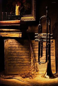 an old trumpet sitting on top of music sheets in front of a painting and candle