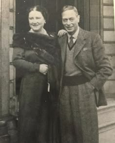 an old black and white photo of two people standing in front of a door with their arms around each other