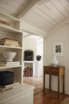 a room with a table, bookshelf and vases on the shelves in it