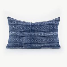 a blue and white pillow with an intricate design on the front, sitting against a white background