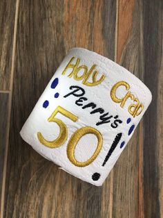 a roll of toilet paper with the number 50 printed on it and gold foil lettering